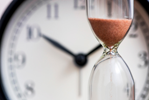 Sand hourglass with working clock in the background - Essence of Time Meaning - Poh Ern Si blog