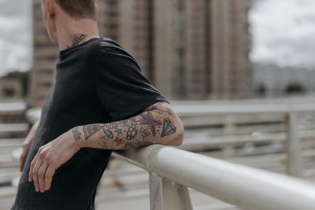 Man dressed in black shirt and arms full of tattoo standing against the rail - What Is Spiritual Vibration, How to Raise Spiritual Vibrations - Poh Ern Si Buddhist Blog