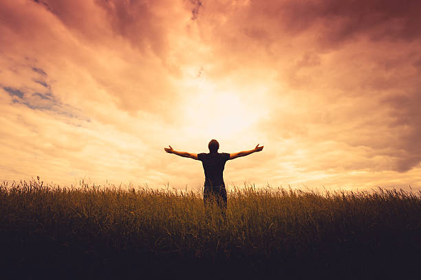 Man standing in a field with open arms - What Is Spiritual Vibration, How to Raise Spiritual Vibrations - Poh Ern Si Buddhist Blog